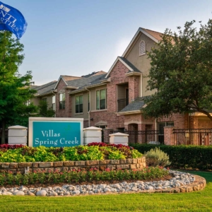 Tonti Properties flag waving over beautifully landscaped front entrance sign