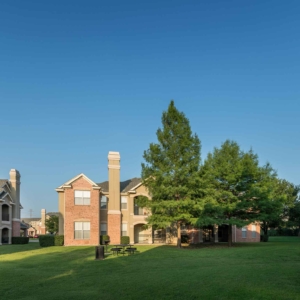 Bright green grass in a courtyard at Villas with picnic area and building in the background