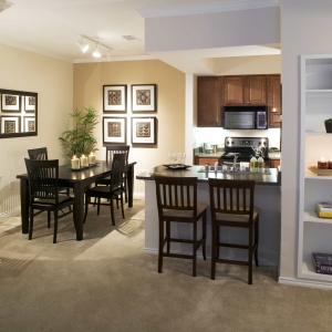 dining area and peek into kitchen at a home at villas, built in bookshelves and stainless and black appliances
